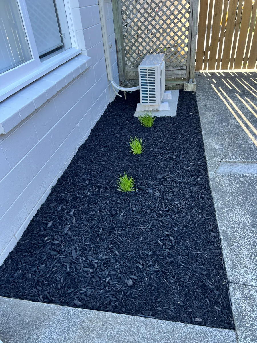 A fresh stone-and-mulch decorative bed finished against a house, Auckland